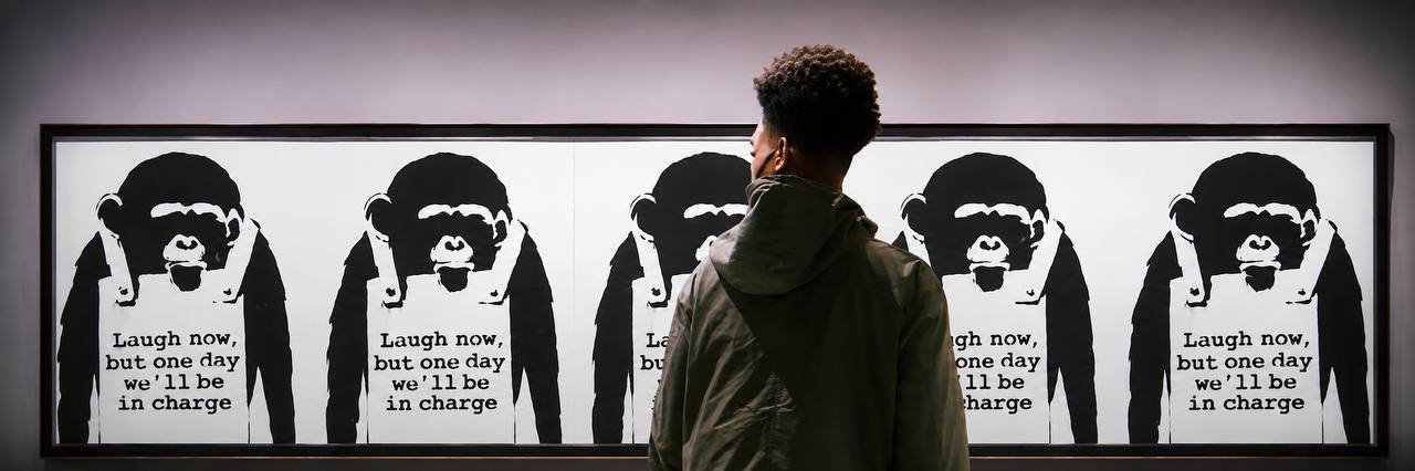Gallery visitor facing a repeated stencil artwork